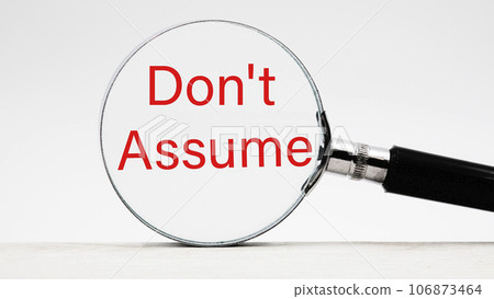 Don't Assume text through a magnifying glass on a light background Don't Assume text through a magnifying glass on a light background 106873464