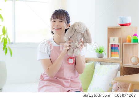 苗圃肖像一名拿著毛絨動物對著鏡頭微笑的護士 苗圃肖像一名拿著毛絨動物對著鏡頭微笑的護士 106874268