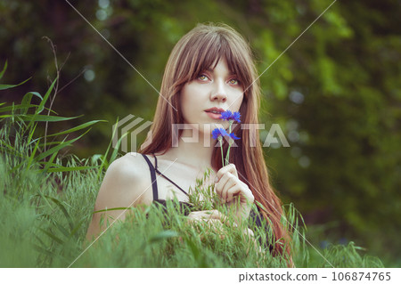 There is a beautiful woman in a meadow among the grass. 106874765