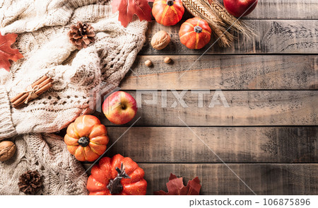 Autumn and thanksgiving decoration concept made from autumn leaves and pumpkin on dark wooden background. Flat lay, top view with copy space. 106875896