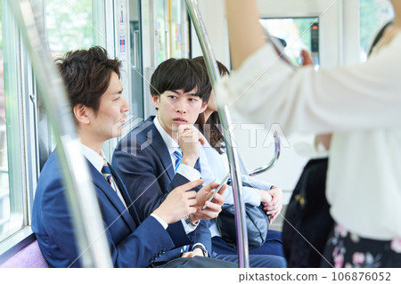 A man talking on a train. Photography provided by Keio Electric Railway Co., Ltd. 106876052