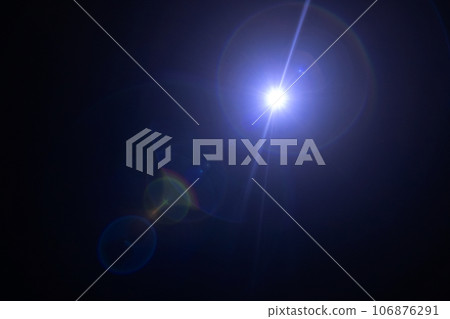 Glare on a black background. A camera pointed at the light produces a special flare effect. A ray of sunshine and a rainbow spectrum of colors. Shimmers and gradients. Optical illusion 106876291