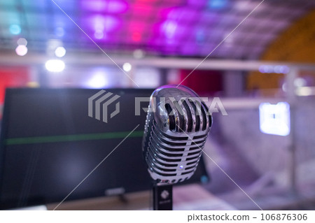 Microphone for karaoke. Close-up of a metal recording device against the backdrop of a studio or karaoke bar. Blurred background and emphasis on the device 106876306