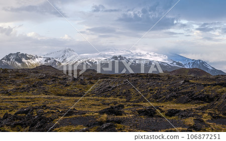View during auto trip in West Iceland, Snaefellsnes peninsula, View Point near Svortuloft Lighthouse. Spectacular black volcanic rocks and snowy Snaefellsjokull Volcano in far. View during auto trip in West Iceland, Snaefellsnes peninsula, View Point near Svortuloft Lighthouse. Spectacular black volcanic rocks and snowy Snaefellsjokull Volcano in far. 106877251