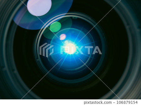 Close up of camera lens with lens flare light a blue. Abstract light natural flare in a camera lens. 106879154