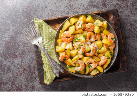 Homemade spicy fried potatoes with shrimp, parsley and garlic close-up in a plate. Horizontal top view Homemade spicy fried potatoes with shrimp, parsley and garlic close-up in a plate. Horizontal top view 106879380