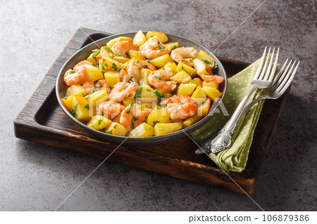 Homemade spicy fried potatoes with shrimp, parsley and garlic close-up in a plate. Horizontal 106879386