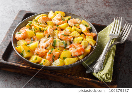 Spanish Potatoes roasted with Garlic Shrimp close-up in a plate. Horizontal 106879387
