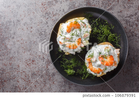 Baked potatoes stuffed with sour cream sauce, garlic, dill and shrimp close-up in a plate. Horizontal top view 106879391