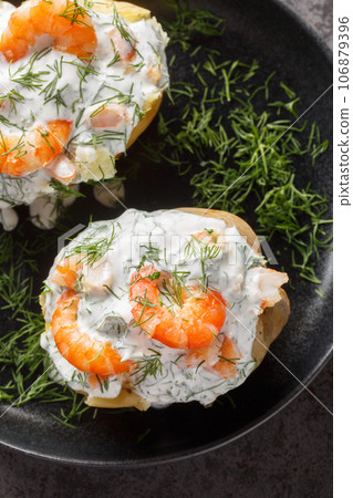 Swedish jacket potatoes with sour cream sauce and shrimp close-up in a plate. Vertical top view Swedish jacket potatoes with sour cream sauce and shrimp close-up in a plate. Vertical top view 106879396