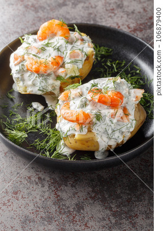 Delicious jacket potatoes with sour cream sauce, dill and shrimp close-up in a plate. Vertical Delicious jacket potatoes with sour cream sauce, dill and shrimp close-up in a plate. Vertical 106879400