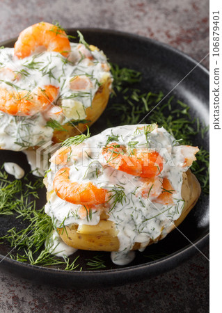 Baked potato with sour cream and prawns close-up in a plate. Vertical Baked potato with sour cream and prawns close-up in a plate. Vertical 106879401