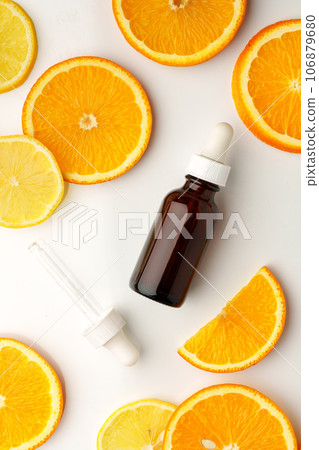 Glass bottle of essential citrus oil on oranges background 106879680