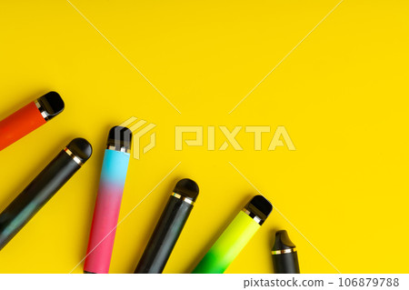 Colorful disposable electronic cigarettes on yellow background 106879788