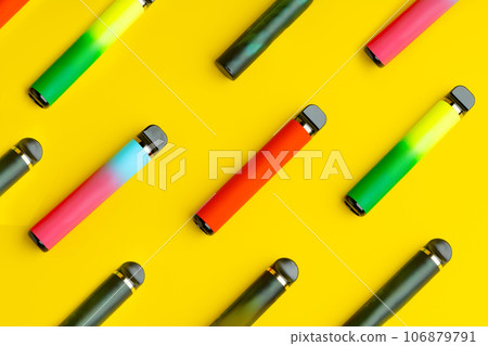 Colorful disposable electronic cigarettes on yellow background 106879791