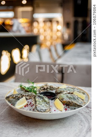 Plate with oysters on ice and sauce on a marble table 106879864