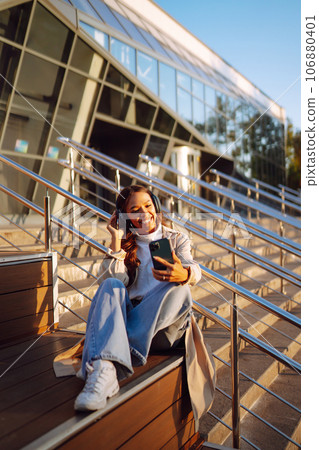 Young woman listening to music with headphones outdoors. The concept of people, music, emotions. Young woman listening to music with headphones outdoors. The concept of people, music, emotions. 106880401