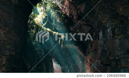 A stunning cave illuminated by volumetric light, showcasing a lush green plants A stunning cave illuminated by volumetric light, showcasing a lush green plants 106880966