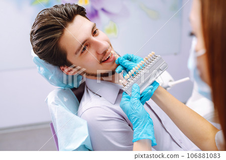 Young man at the dentist's chair during a dental procedure. Overview of dental caries prevention. 106881083