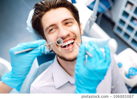 Young man at the dentist's chair during a dental procedure. Overview of dental caries prevention. Young man at the dentist's chair during a dental procedure. Overview of dental caries prevention. 106881087