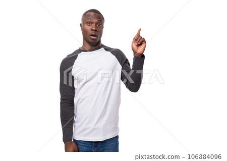 young positive african man dressed in a spring jacket tells interesting news and points with his young positive african man dressed in a spring jacket tells interesting news and points with his 106884096