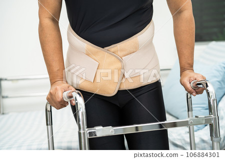 Asian lady patient wearing back pain support belt for orthopedic lumbar with walker. 106884301