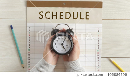 Girl's hand holding a clock on the calendar. Appointments, schedules, plans, reservations, etc. 106884596