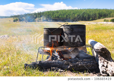 Cooking camp food in cauldrons on open fire Cooking camp food in cauldrons on open fire 106885419