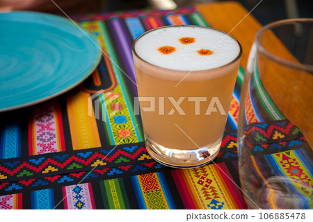 Pisco Sour cocktail in glass on placemat with traditional pattern 106885478