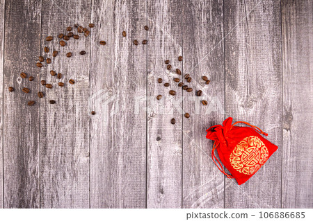 Coffee beans scattered from a silk red bag on grey boards Coffee beans scattered from a silk red bag on grey boards 106886685