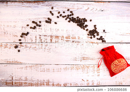 Coffee beans scattered from a silk red bag on white boards 106886686
