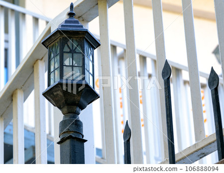 An old-fashioned street lamp on a metal fence. An old-fashioned street lamp on a metal fence. 106888094