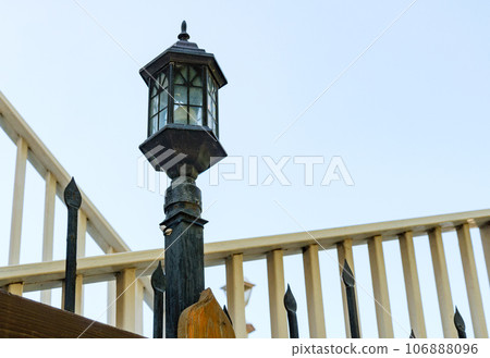 An old-fashioned street lamp on a metal fence. An old-fashioned street lamp on a metal fence. 106888096