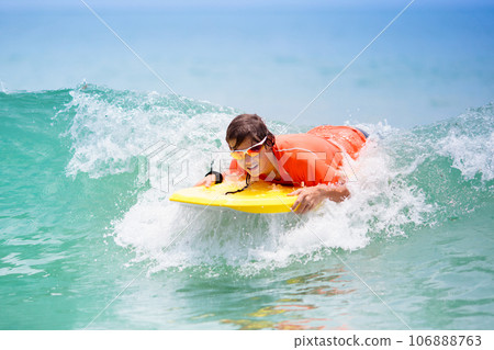 Child surfing on tropical beach. Surfer in ocean. 106888763
