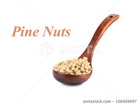 Peeled pine nuts in a wooden spoon on a white background with the inscription - Pine nuts. Peeled pine nuts in a wooden spoon on a white background with the inscription - Pine nuts. 106889097