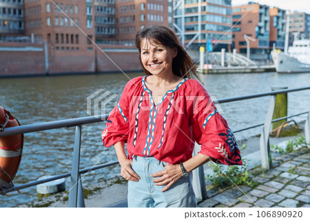 Mature smiling woman in embroidered shirt looking at camera, outdoor 106890920