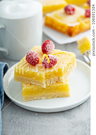 Homemade lemon bars topped with powdered sugar and raspberries 106891384