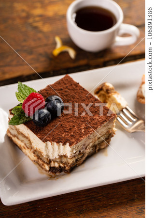 Tiramisu dessert served on a white plate with espresso Tiramisu dessert served on a white plate with espresso 106891386