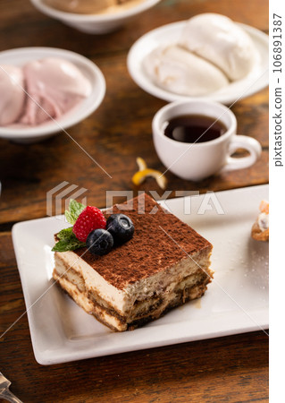 Tiramisu dessert served on a white plate with espresso Tiramisu dessert served on a white plate with espresso 106891387