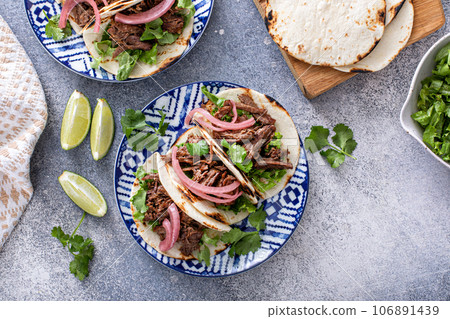 Beef tacos with lettuce and pickled red onion 106891439