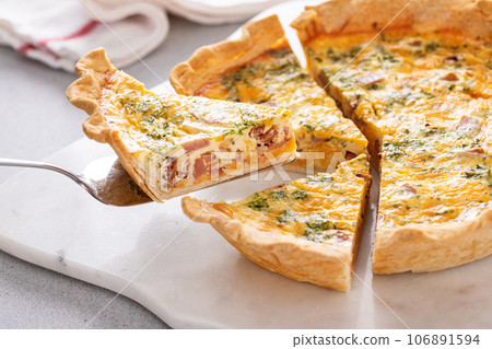 Homemade quiche with ham and cheese cut on the table Homemade quiche with ham and cheese cut on the table 106891594
