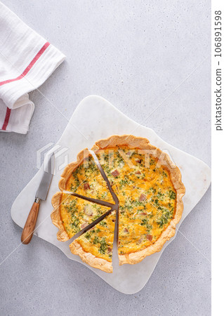 Homemade quiche with ham and cheese cut on the table Homemade quiche with ham and cheese cut on the table 106891598