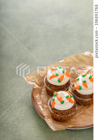 Carrot cupcakes with cream cheese frosting decorated with tiny carrots Carrot cupcakes with cream cheese frosting decorated with tiny carrots 106891768