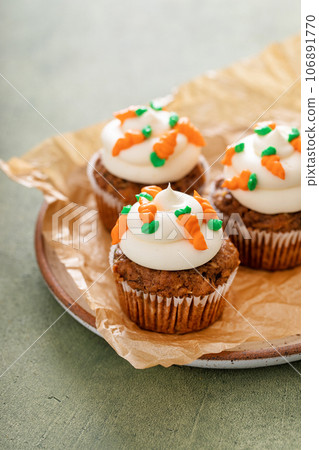 Carrot cupcakes with cream cheese frosting decorated with tiny carrots 106891770