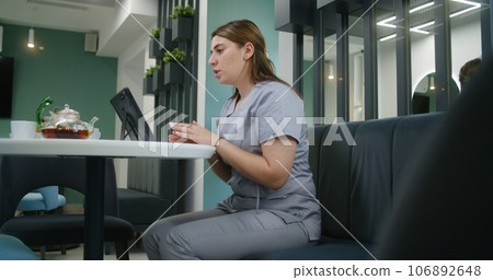 Female doctor consults patient via video call in hospital canteen 106892648
