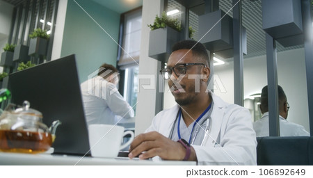 African American doctor uses laptop in modern clinic cafe 106892649