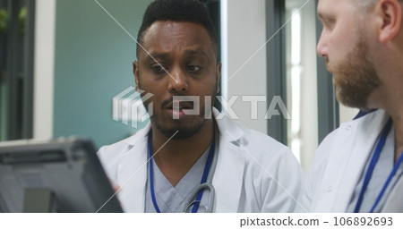 Multiethnic doctors examine medical tests results on tablet in clinic cafe Multiethnic doctors examine medical tests results on tablet in clinic cafe 106892693