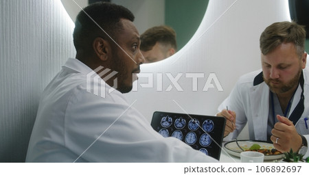 African American doctor uses tablet with MRI scan image near colleagues African American doctor uses tablet with MRI scan image near colleagues 106892697