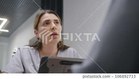 Female doctor sits in clinic cafe at meeting with patient, uses digital tablet Female doctor sits in clinic cafe at meeting with patient, uses digital tablet 106892713