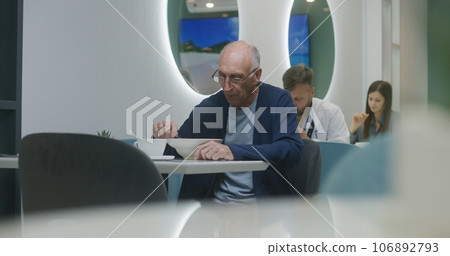 Senior patient sits in hospital cafeteria and eats meal 106892793